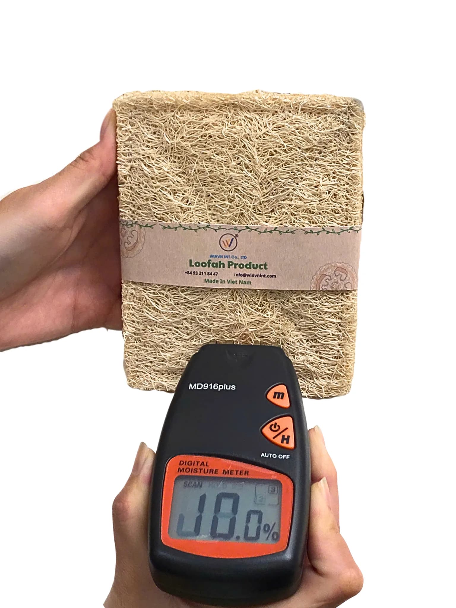 Digital moisture meter reading 8.0% on a branded loofah block
